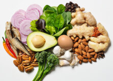 Healthy food on a platter (nuts, peppers, spinach, avocado, eggs, and ginger).